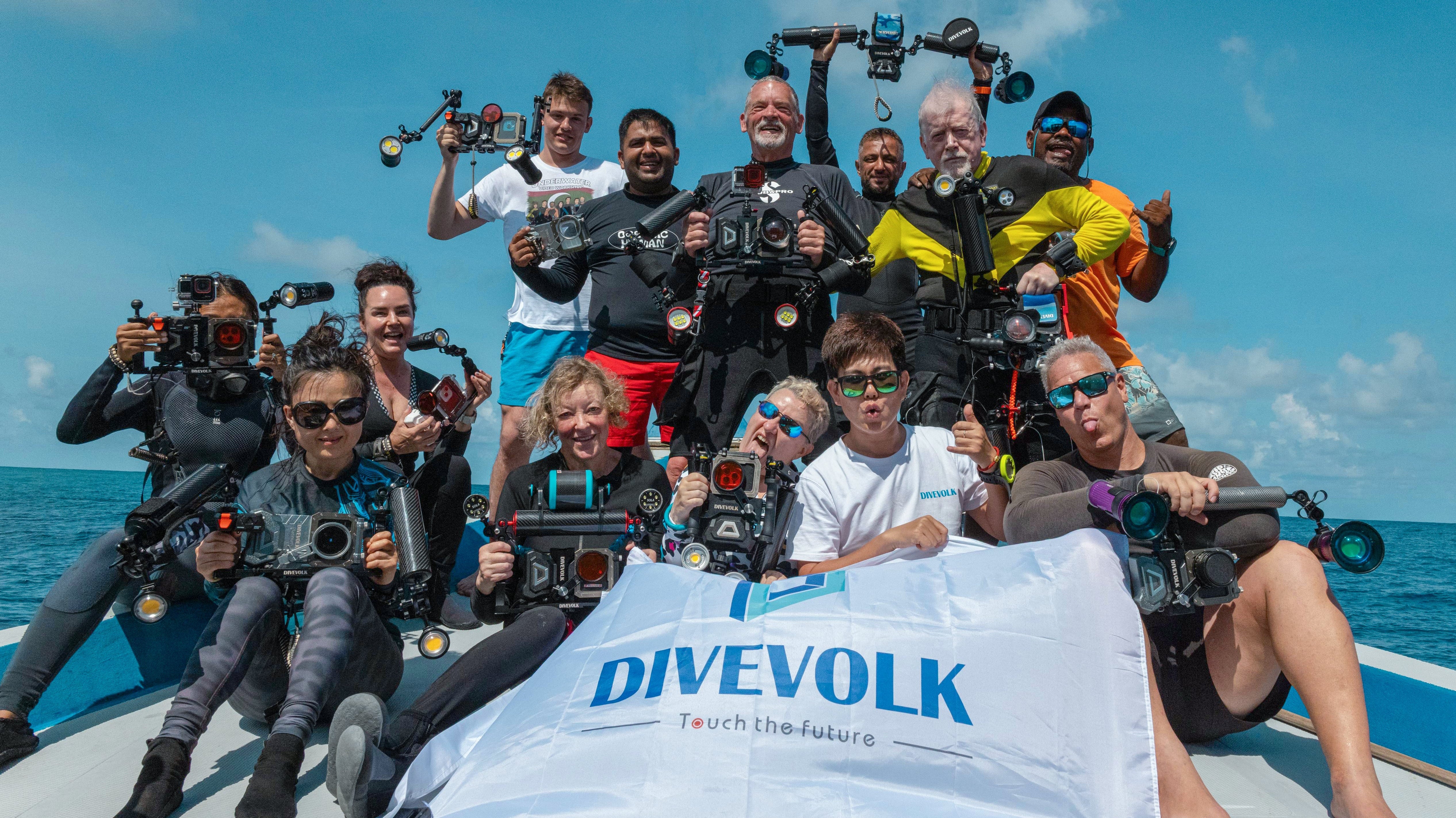 Group of people on a boat with filming equipment and a Divevolk banner