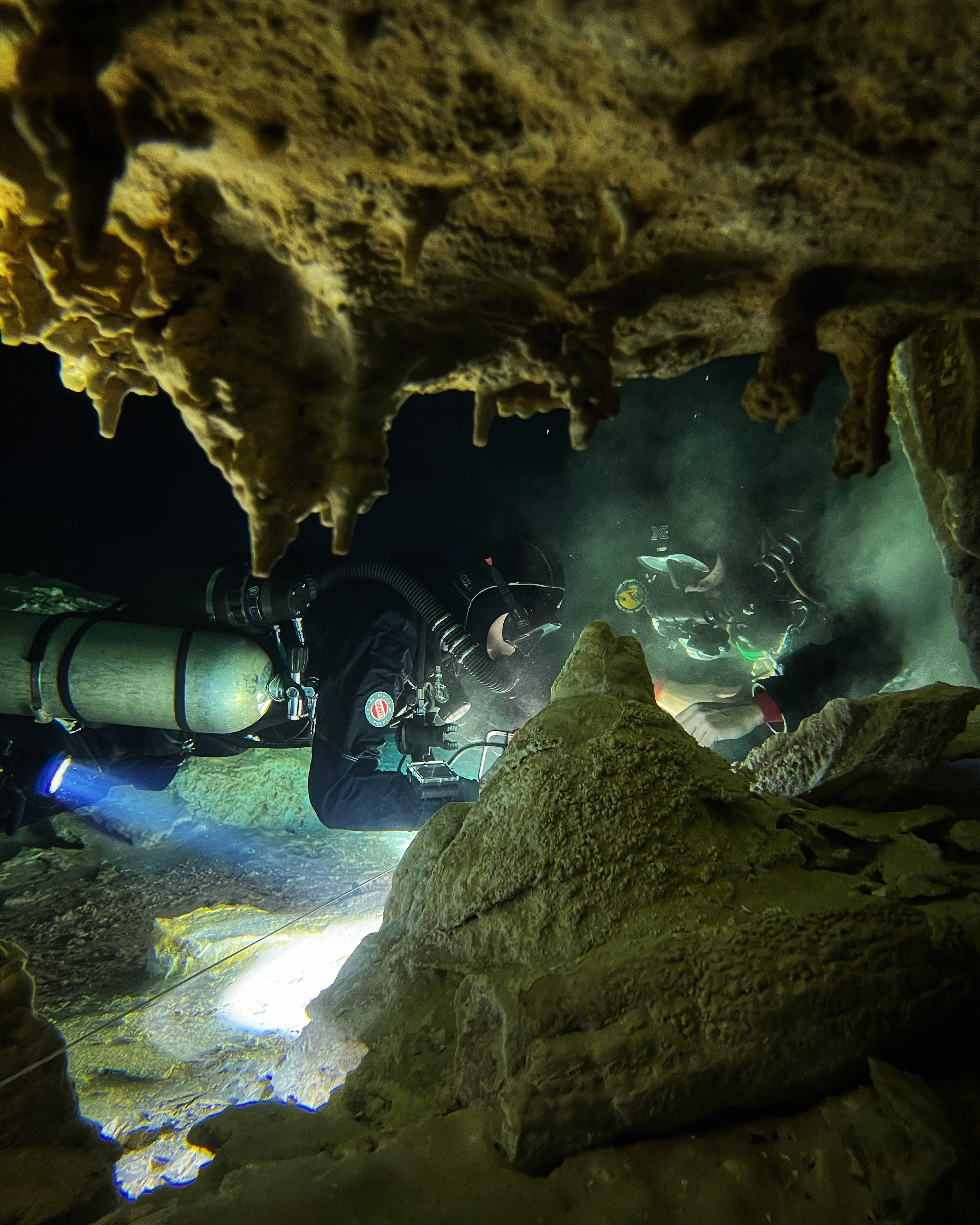A diver exploring an underwater cave with the SeaTouch 4 Max Plus Housing, capturing the mysterious atmosphere and intricate details of the cave's interior with clear visibility and dramatic lighting.