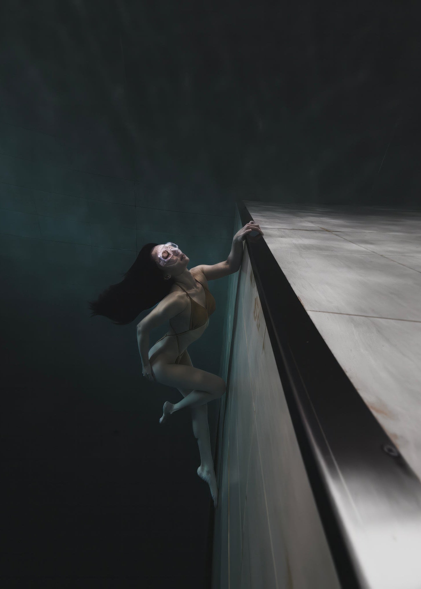 A model elegantly posed underwater near a pool edge, captured with the SeaTouch 4 Max Plus Housing, showcasing the clarity and detail of underwater fashion photography with a focus on human subjects.