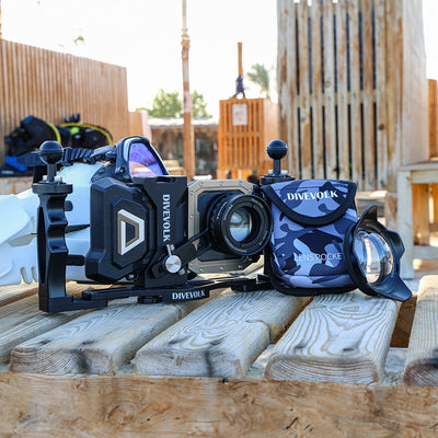 The DIVEVOLK camouflage lens pocket shown in an outdoor beach setting with a dive housing.