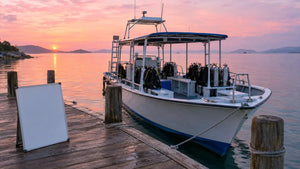 Dive boat moored at a wooden dock at dawn with a blank whiteboard