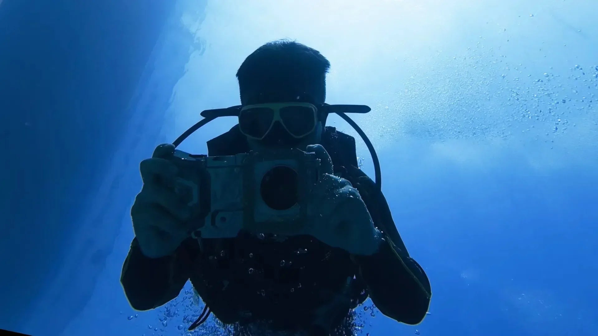 Backlit silhouette of a scuba diver filming with a vivo X Fold6 in a DIVEVOLK SeaTouch 4 Max Platinum V2 housing at Belize's Great Blue Hole