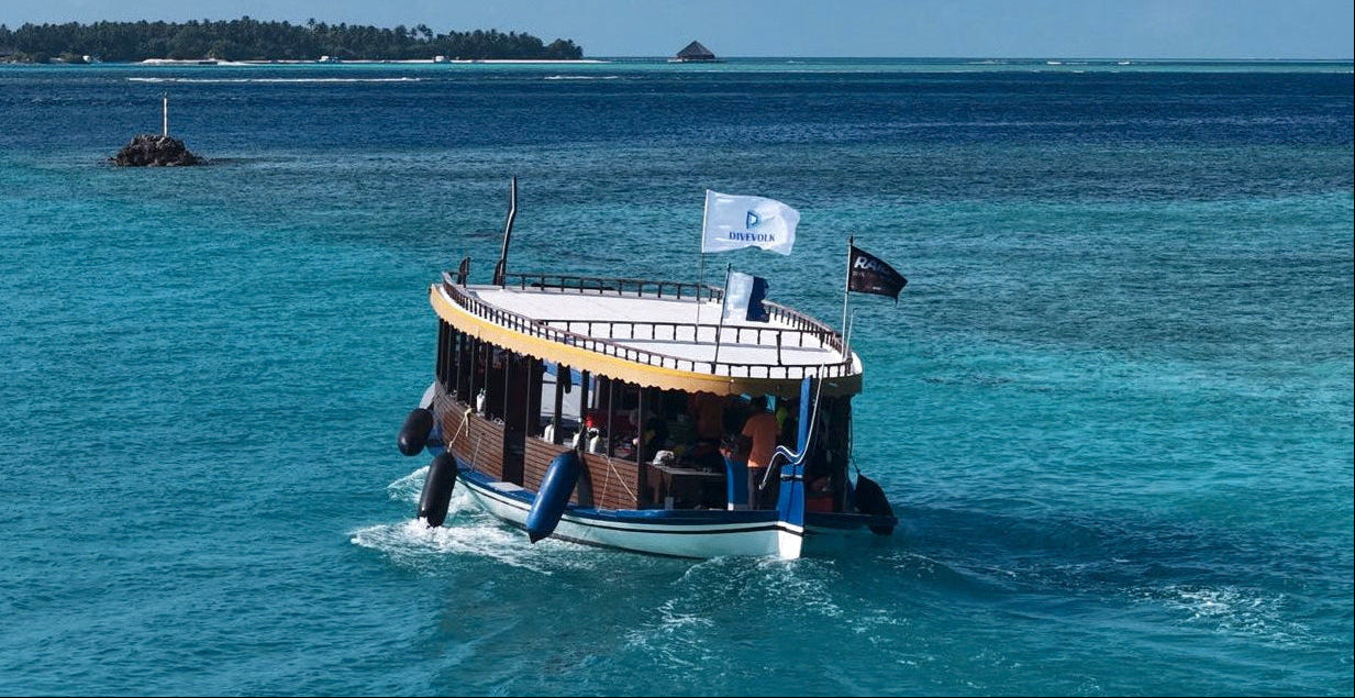 Boat on a clear blue ocean with a distant island ,with a DIVEVOLK flag